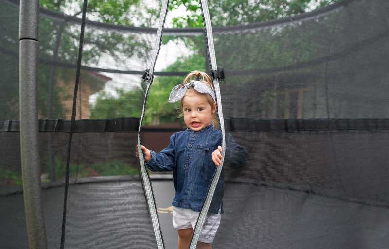 happy little girl on the playground with trampoline
