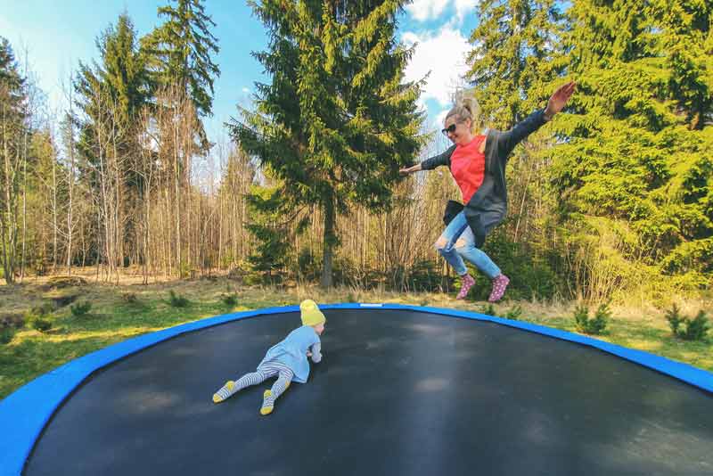mother and daughter jumping on trampoline outdoors