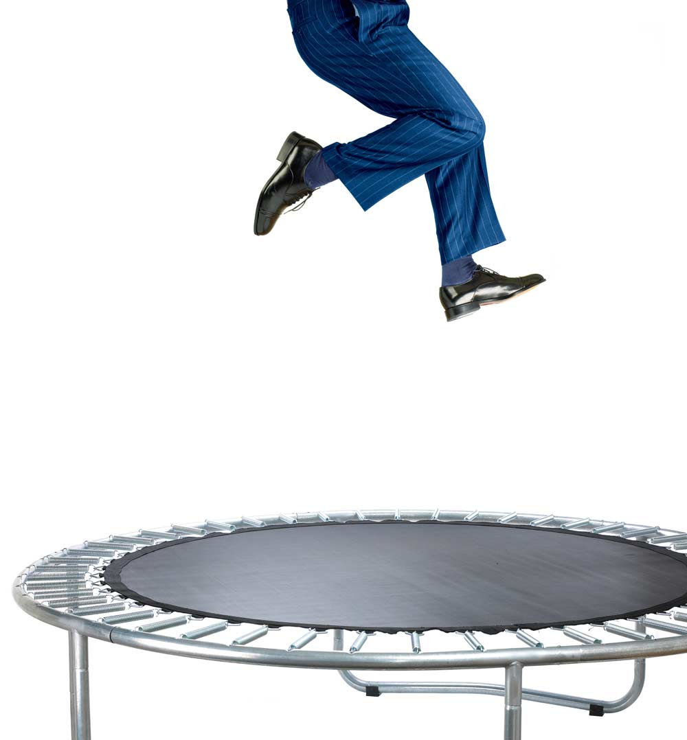 businessman jumping on small trampoline