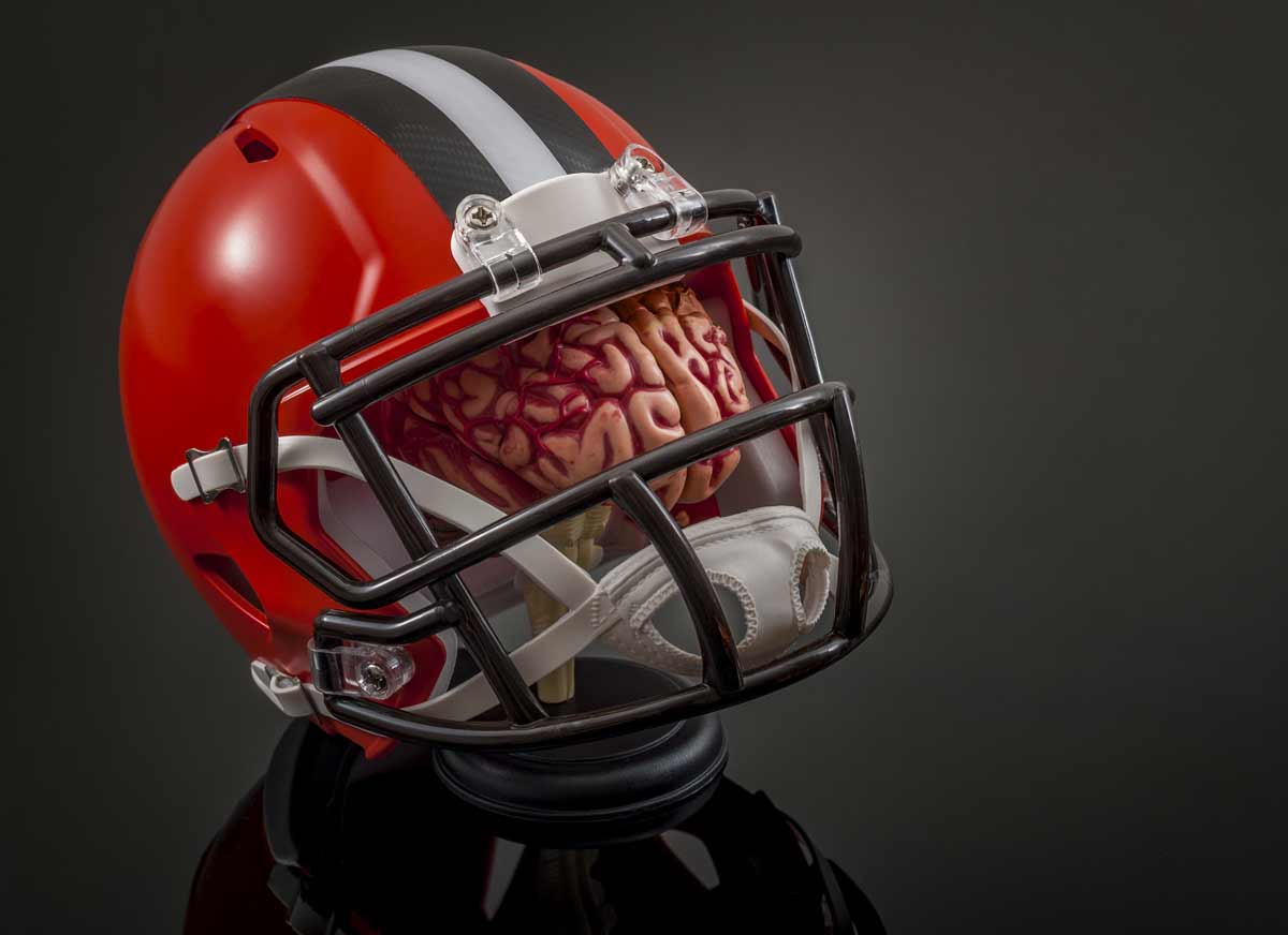 American football concussion protocol concept with a brain wearing a football helmet for protection 