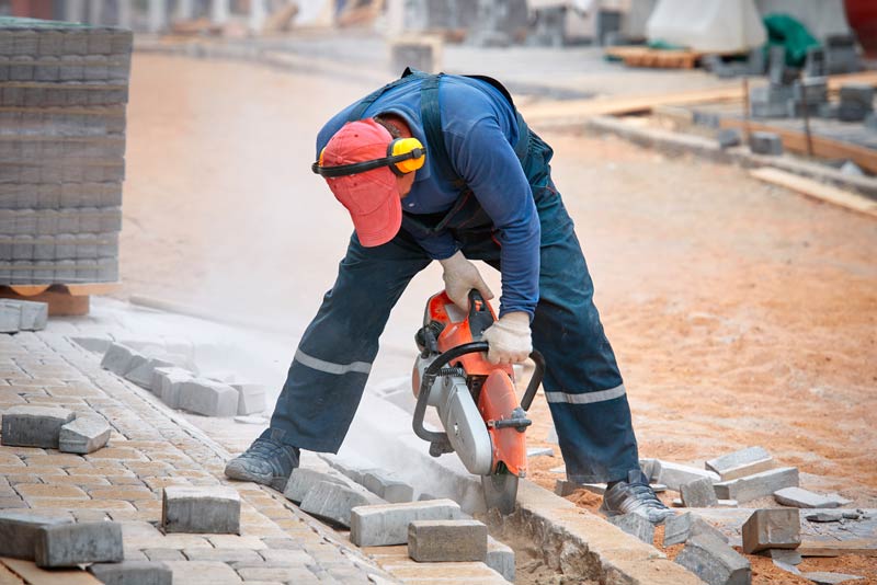 construction worker cuts walkway with circular saw  creating noise hazard