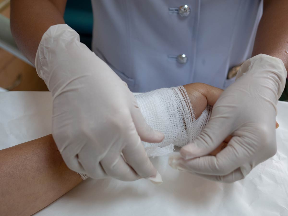 doctor bandaging patient after cleaning wound