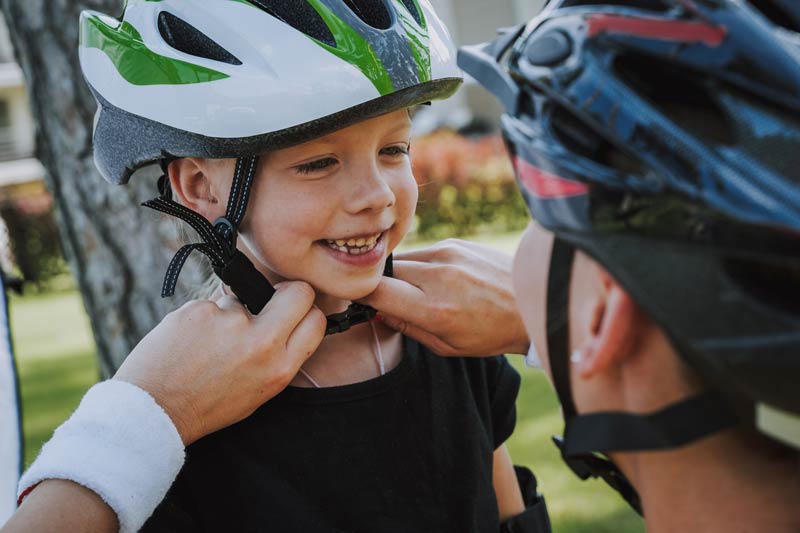 mother helps child put on helmet