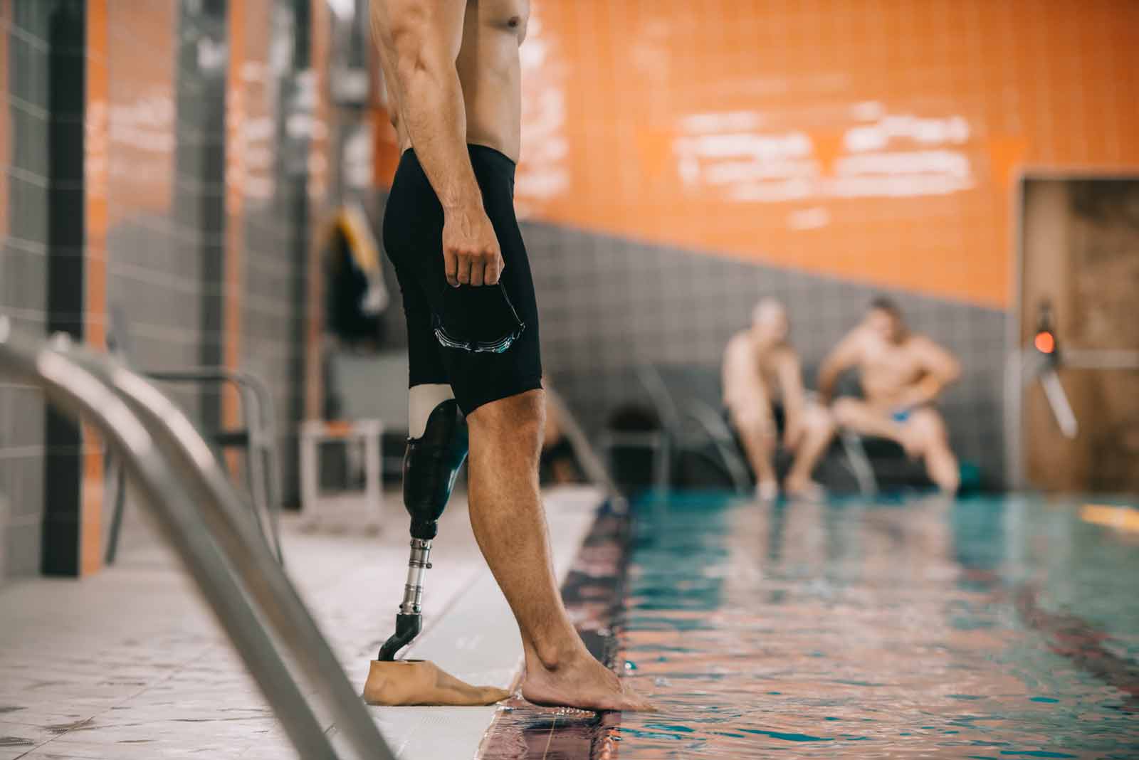 sportsman with prosthetic leg standing on poolside