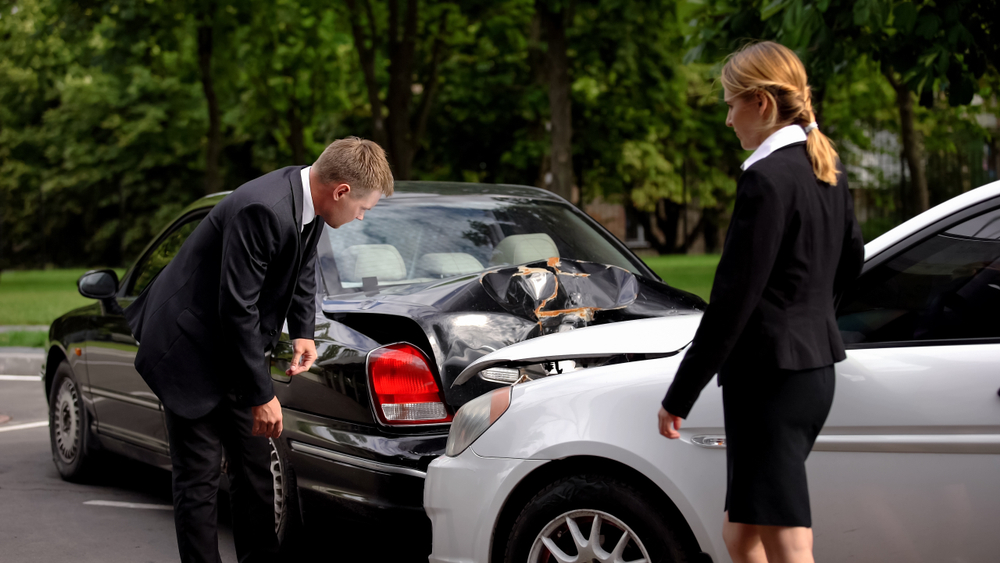 Two people standing beside a damaged car after an accident