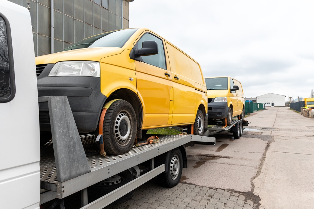Yellow van loaded on a flatbed tow truck