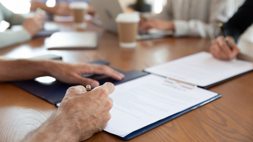 Person signing a document at a table