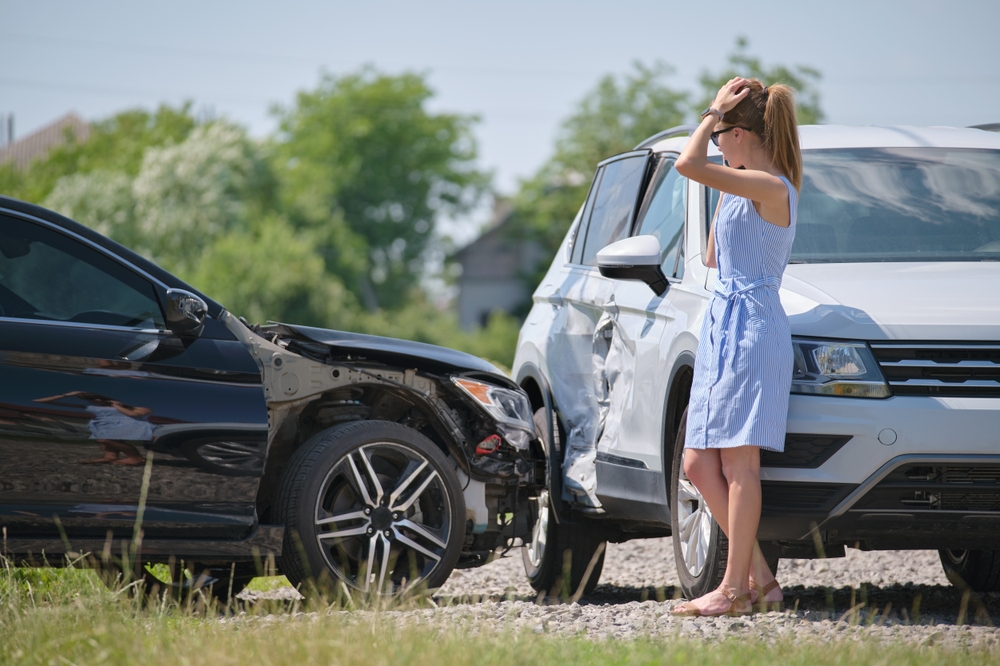 Woman talking on a phone beside two cars damaged in a collision