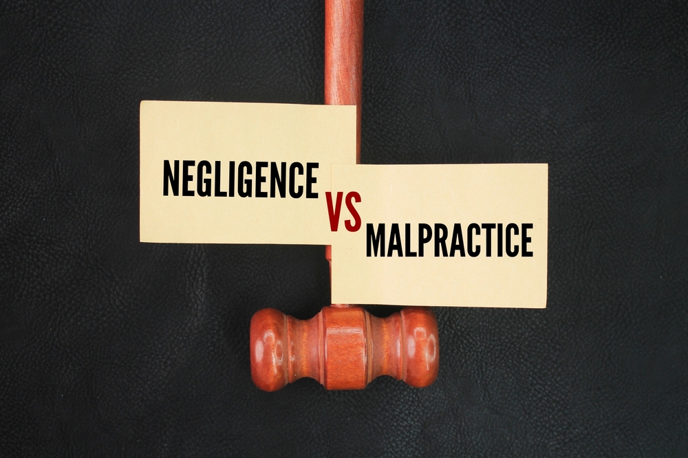 Signs reading Negligence vs Malpractice above a wooden gavel