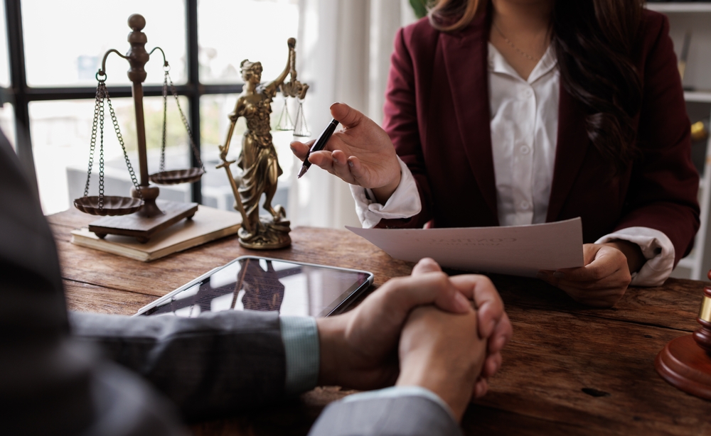 Person at a desk with a Lady Justice statue and a gavel, in a law office