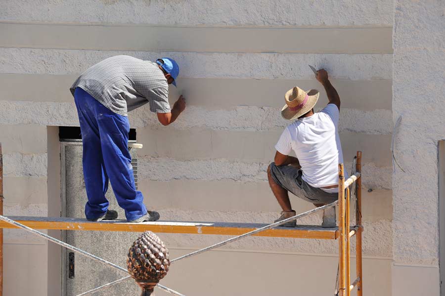 two men working on scaffolds building house