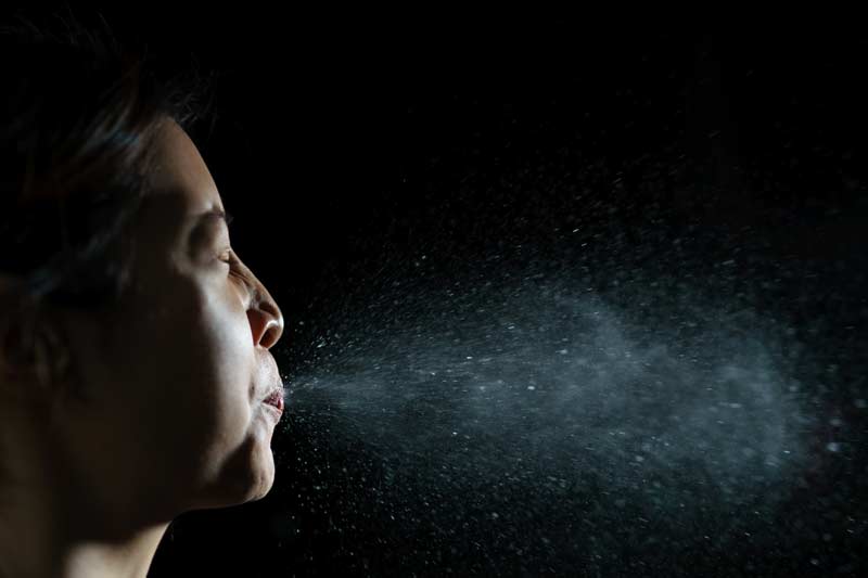 woman coughing or sneezing. allowing spread of the virus -by spray infection